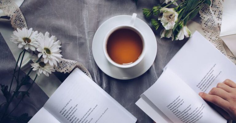 Poetry Readings - White Ceramic Teacup With Saucer Near Two Books Above Gray Floral Textile