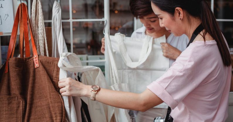 Sustainable Fashion - Trendy young Asian women choosing cotton bags in fashion boutique