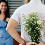 Fashion Blogs - Man Holding Baby's-breath Flower in Front of Woman Standing Near Marble Wall