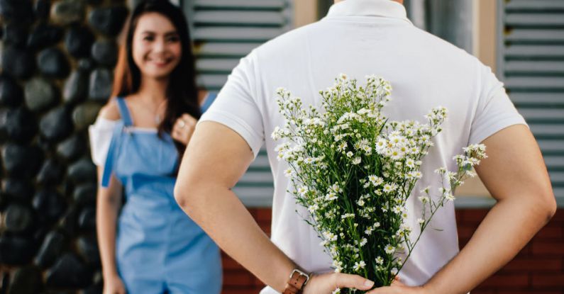 Fashion Blogs - Man Holding Baby's-breath Flower in Front of Woman Standing Near Marble Wall