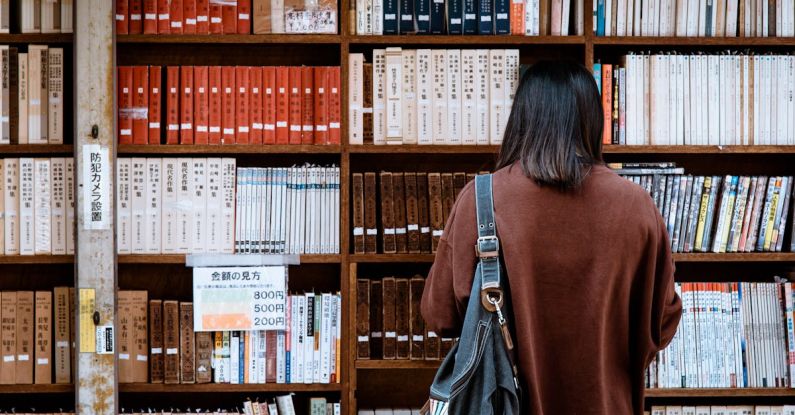 University - Woman Wearing Brown Shirt Carrying Black Leather Bag on Front of Library Books