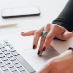 Startup Scene - Crop female using touchpad on laptop in office