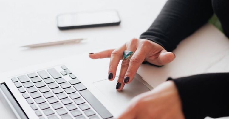 Startup Scene - Crop female using touchpad on laptop in office