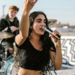 Indie Music - Woman in Black Tank Top and Blue Denim Jeans Sitting on Black and White Drum Set