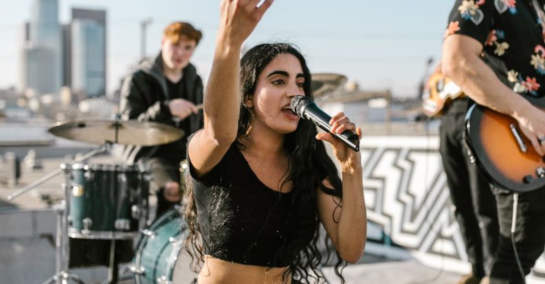 Indie Music - Woman in Black Tank Top and Blue Denim Jeans Sitting on Black and White Drum Set