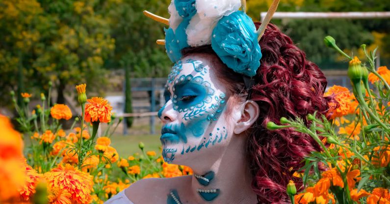 Notting Hill Carnival - Portrait of a Woman in a Blue Traditional Mask and Orange Flowers