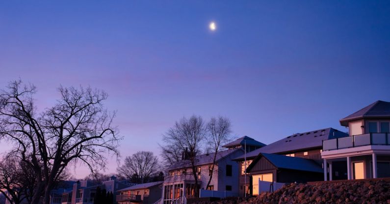 Neighborhoods - A moon rises over a house and a lake